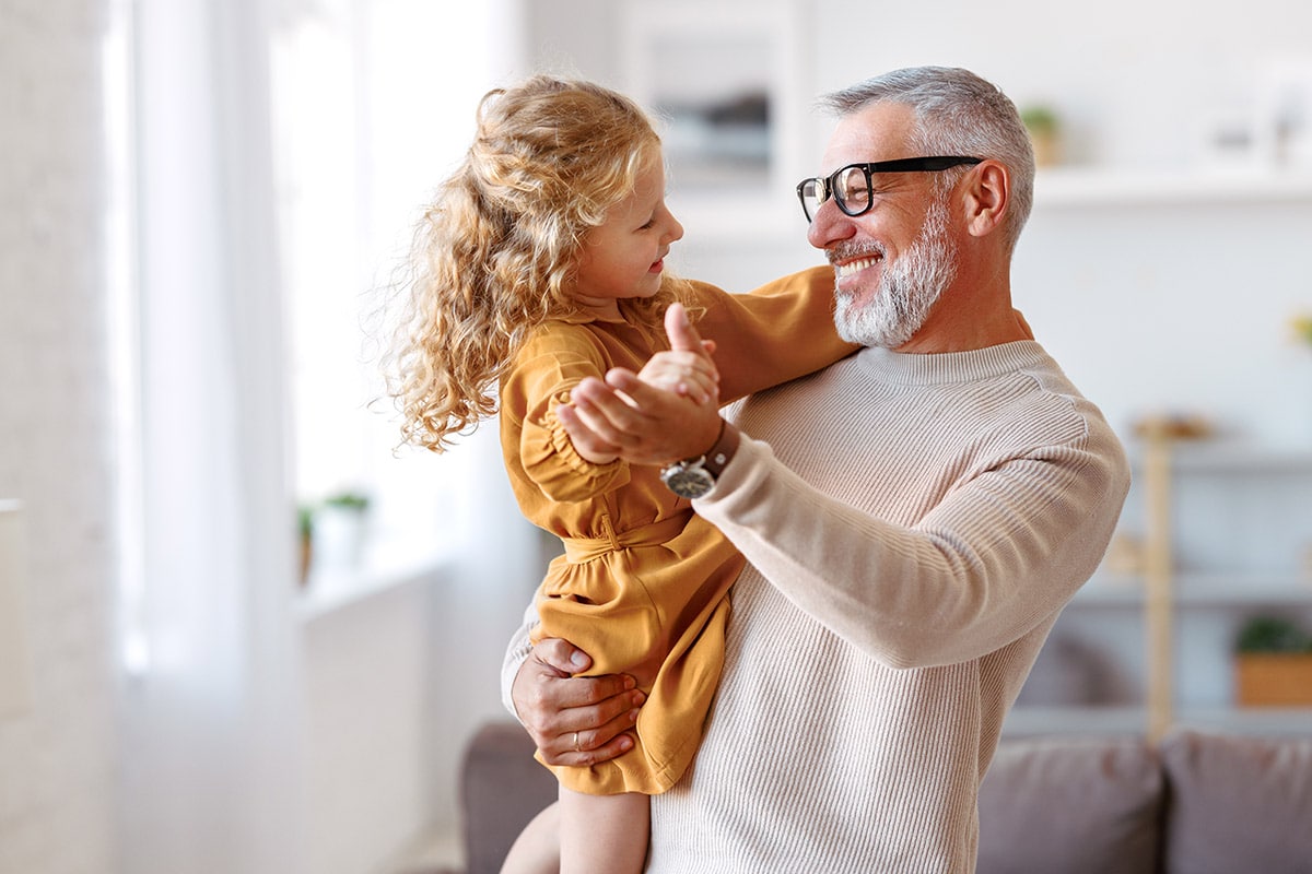 Grandfather holding young granddaughter at home, symbolizing multi-generational wealth transfer and family legacy planning